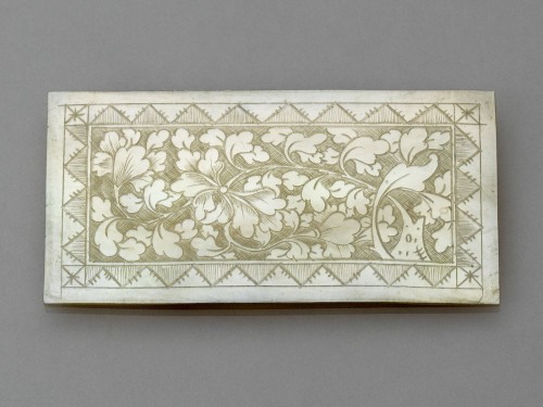 Langwerpig rechthoekig plaatje  van parelmoer met blad- en bloemranken
