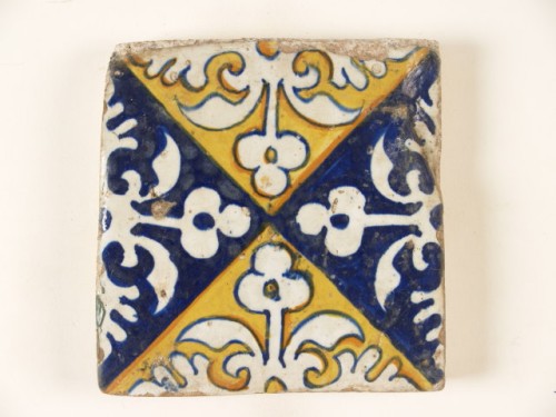 Tegel met een uitgespaard ornamentdecor op een blauw en geel fond