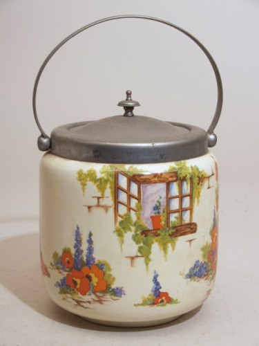 Koektrommel met polychroom decor van bloemen tegen huismuur met raam; 'Old Cottage Window'