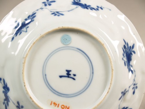 Schotel met geschulpte rand met decor van granaatappelvormige vlakken met bloemranken en rotspartij