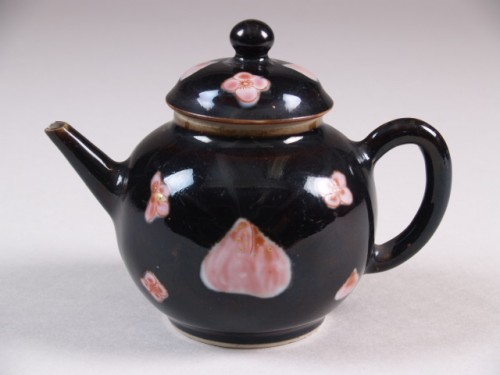 Trekpot met decor van roze bloemen en perziken tegen mirrorblack-fond