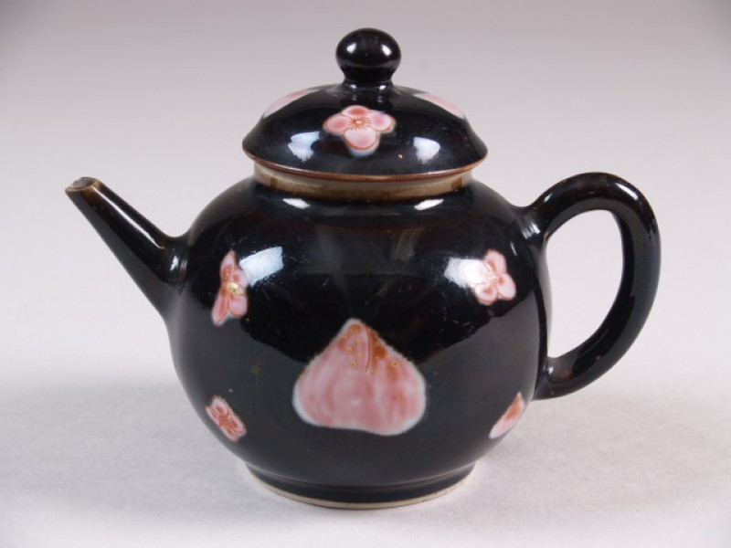 Trekpot met decor van roze bloemen en perziken tegen mirrorblack-fond